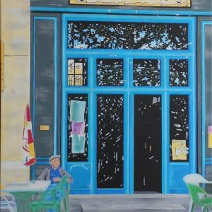 Café Des Arts - Café der Künste - zeigt ein französisches Café in der Stadt Sault in der Provence. Azurblaue Fenster-und Türrahmen, Spiegelungen der Bäume in den Fenstern, ein Sommertag. Vor dem Café sitzt ein typischer Franzose mit Baskenmütze und trinkt einen Café.